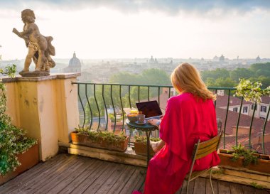 Bilgisayar ile balkonda çalışan kadın