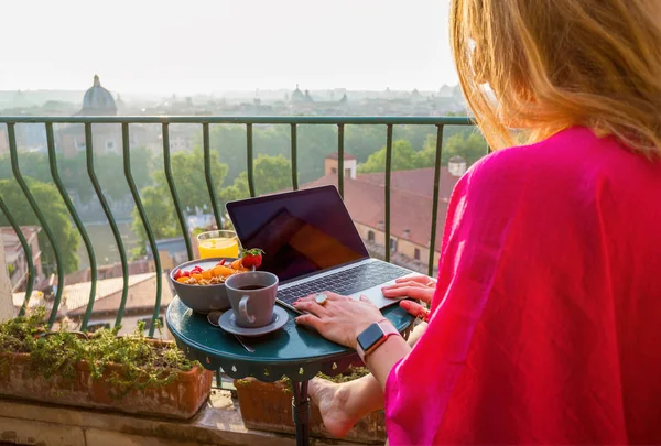 バルコニーで朝食中にラップトップを使用しての女性 — ストック写真