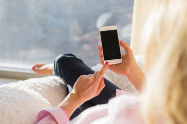 Evde akıllı telefon kullanan bir kadın.