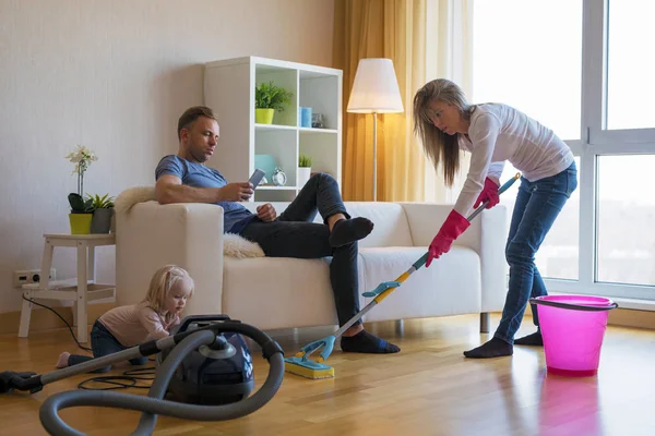 Donna Pulizia Pavimenti Casa Mentre Suo Uomo Pigro Seduto Sul — Foto Stock