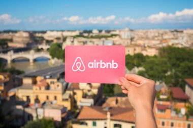 Rome, İtalya - 13 Mayıs 2018: Airbnb logosu ile arka plan şehirde elinde tutan kişi.