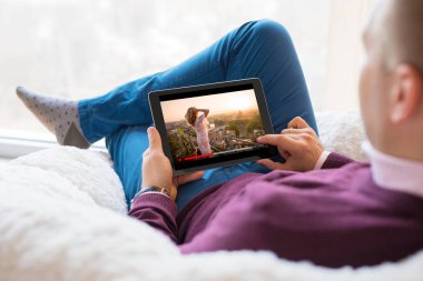 Tablet evde film izlerken adam.