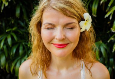 Kapalı gözlerinin önünde tropikal yeşil yeşillik olan kadın. Vintage fotoğraf filtresi uygulanmış.