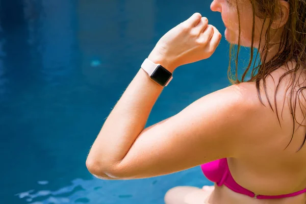 手持数字手表的女人在游泳池边上 — 图库照片