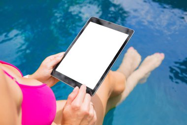 Havuz kenarında oturan ve tablet bilgisayar kullanarak bir kadın. Dikey perde kadar sahte.