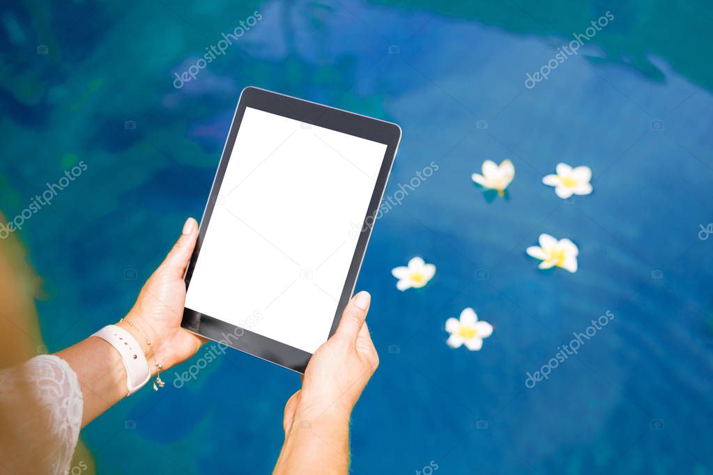 Woman sitting by the pool and using tablet computer. Vertical white screen .