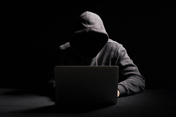 Hacker working on laptop in the dark