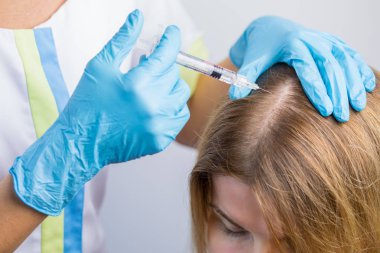 Mezoterapi prosedürü. Doktor kozmetolojist güçlü ve sağlıklı saçlar için kadının kafasına enjeksiyon lar yapıyor.