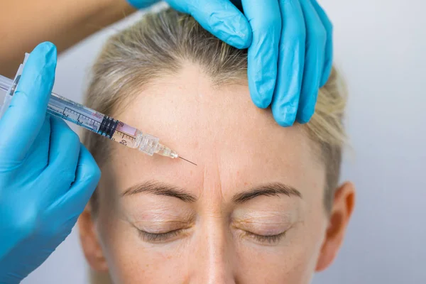 医生使恢复活力的面部注射 以平滑妇女的额头皮肤 — 图库照片