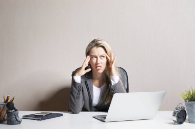 Ofis masasında oturan stresli ve yorgun bir kadın.