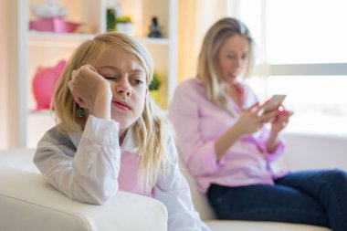 Annesi telefon kullanırken küçük kız sıkılıyor.