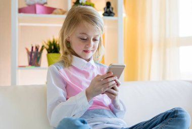 Mutlu kız kanepede oturuyor ve evde telefon kullanıyor.