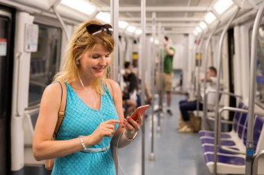 Kadın metroya biniyor ve cep telefonu kullanıyor.