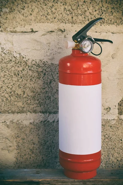 Compact red fire extinguisher for auto or home on grey background. For fire emergencies