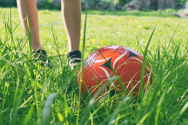 Zamknij Widok Chłopca Nogi Czerwoną Piłkę Zielonej Trawie Dzieci Bawiące — Zdjęcie stockowe