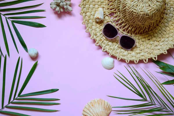 Creative minimal summer idea. Tropical beach concept made of bamboo hat, sunglasses, seashells and green palm leaves on pastel background. Creative art. Flat lay, top view. Copy space.