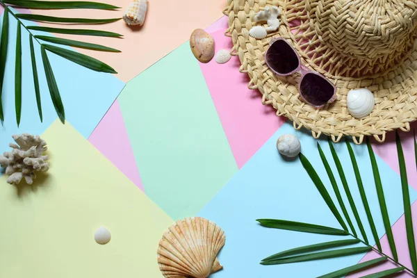 Creative minimal summer idea. Tropical beach concept made of bamboo hat, sunglasses, seashells and green palm leaves on pastel background. Creative art. Flat lay, top view. Copy space.