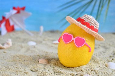 Yaratıcı en az yaz fikir. Bambu şapka, güneş gözlüğü ve plaj şemsiyesi kum içinde limon narenciye hippi. Tropikal plaj kavramı. Yaratıcı sanat. Kopya alanı.