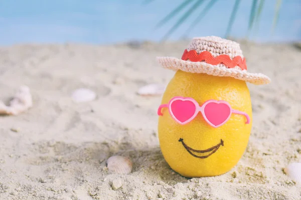 Creative minimal summer idea. Lemon citrus hipster in pink sunglasses and bamboo hat on sand. Tropical beach concept. Creative art. Fun party Mood. Copy space.