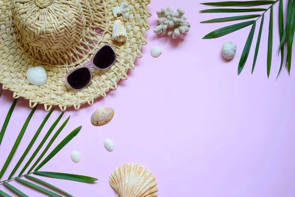 Creative minimal summer idea. Tropical beach concept made of bamboo hat, sunglasses, seashells and green palm leaves on pastel background. Creative art. Flat lay, top view. Copy space.