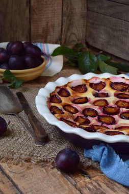 Ahşap arka plan üzerinde beyaz seramik formundaki erik turtası. Homemade Pişirme. Sağlıklı hamur işleri. Vejetaryen yiyecekler. Rustik fotoğraf. Kopya alanı