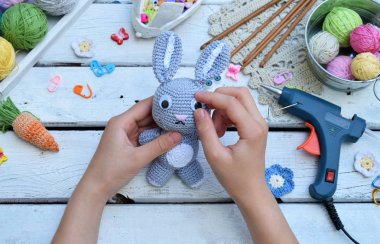 Tavşan havuç ile yapım. Bunny çocuk için tığ işi. Tablo konu üzerinde iğneler, kanca, pamuk ipliği. Adım 3 - oyuncak gözünde tutkal. El yapımı el sanatları. DIY kavramı. Küçük işletme. Hobi geliri