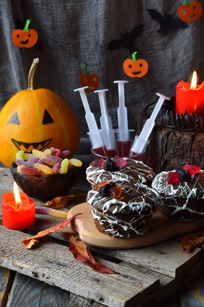 Halloween trick or treat party. Funny delicious sweets and pumpkin on wooden background - muffins, cupcakes, juice, jellies, candy