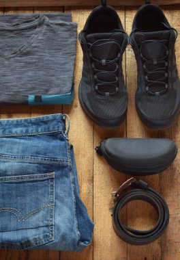 Erkekler rahat kıyafetler. Erkek ayakkabı, giyim ve aksesuar ahşap arka plan - gri t-shirt, kot, spor ile gözlük, Ayakkabı kemer. Üstten görünüm. Düz yatıyordu