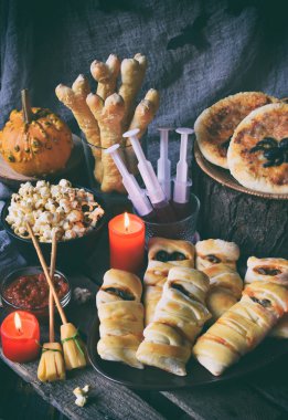 Cadılar Bayramı hüner ya da muamele etmek parti. Komik lezzetli yemekleri ve ahşap arka plan - mini pizza, ekmek sopa, peynir, zeytin, ketçap, patlamış mısır, kabak suyu. Metin için yer kopyalayın