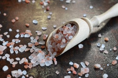Tahta kaşık siyah arka plan üzerine kaba pembe tuz. Himalaya tuz. Kopya alanı.