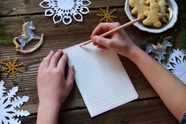 Mektubu Noel Baba için. Dilek listesi. Noel dekorasyonu, kağıt kar taneleri, zencefilli kurabiye adam ahşap arka plan üzerinde. Kış tatil kavramı. Üstten görünüm, kopya alanı.