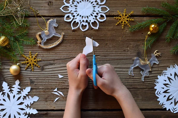 Making paper snowflakes with your own hands. Children's DIY. Merry Christmas and New Year concept. Step 2. Cut the snowflake.