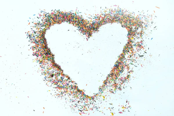 Colorful heart made from shavings of pencils on white background. Ideas with color pencil dust. Copy space.