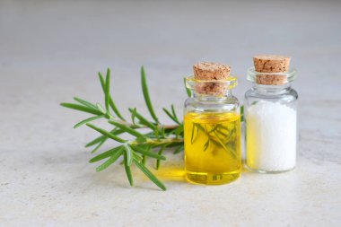 Bir küçük şişe ve ışık arka plan üzerinde taze dal biberiye uçucu yağ. Doğal aroma Kozmetik yağı ve tuz.