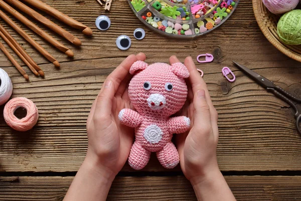Pink Pig. Crochet toy for child. On table threads, needles, hook, cotton yarn. Handmade crafts, DIY concept. Small business. Income from hobby