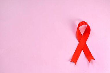 Pembe bir arka plan üzerinde kırmızı kurdele. Dünya AIDS Günü kavramı.