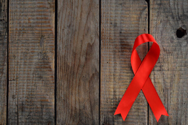 Red ribbon on wooden background. World Aids Day concept.