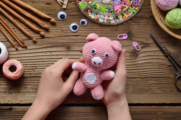 Pink pig. Crochet toy for child. On table threads, needles, hook, cotton yarn. Handmade crafts. DIY concept, Small business. Income from hobby