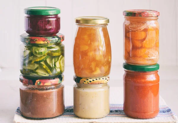 Variety of preserved food in glass jars - pickles, jam, marmalade, sauces, ketchup. Preserving vegetables and fruits. Fermented food. Autumn canning. Conservation of harvest.