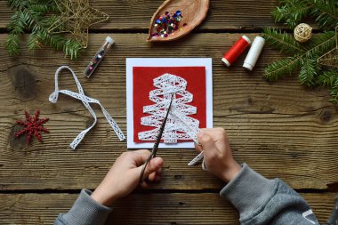 El yapımı Noel tebrik kartı üzerinden kendi elleriyle keçe yapım. Çocuk DIY kavramı. Noel dekorasyon yapma. Adım 1. Ajur kurdele kesmek.