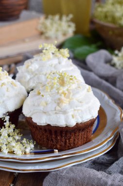 Vanilyalı krema ile çikolata capcakes beyaz çikolata ve mürver çiçekleri ile serpilir. Vintage tarzı. Kopya alanı.