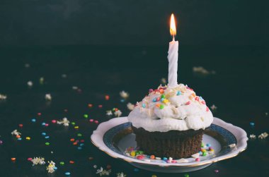 Vanilyalı krema ve mum ile çikolatalı kek. Doğum günün kutlu olsun. Karanlık fotoğraf.