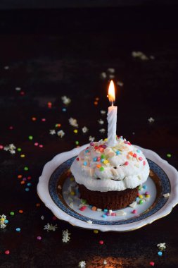 Vanilyalı krema ve mum ile çikolatalı kek. Doğum günün kutlu olsun. Karanlık fotoğraf.