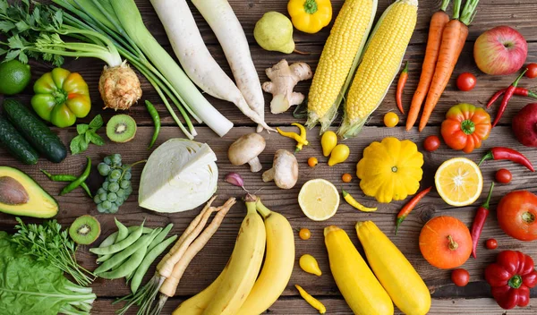 White, green, yellow orange, red fruits and vegetables on wooden background. Healthy food. Multicolored raw food. Copy space.