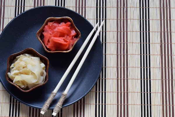 Eingelegte Ingwerscheiben und Stäbchen aus Holz. Zutat für Sushi. Gesunde Ernährung. traditionelle japanische Würze. — Stockfoto