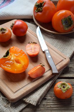 Hurma ahşap arka plan üzerinde farklı çeşitleri. Lezzetli olgun turuncu Trabzon hurması. Organik meyve. Uzay kopyalayın. Seçici odak