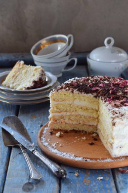 Lezzetli Hindistan cevizi katman pasta - bisküvi ve Hindistan cevizi kreması, krema rendelenmiş çikolata ile dekore edilmiş ve gül yaprakları şekerlenmiş.