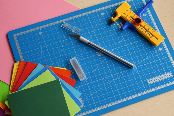 Attrezzature e strumenti per il taglio della carta: coltello da taglio, taglierina affilata, piastra di taglio blu, carta origami. Moderno stile arte carta origami 3d . — Foto Stock