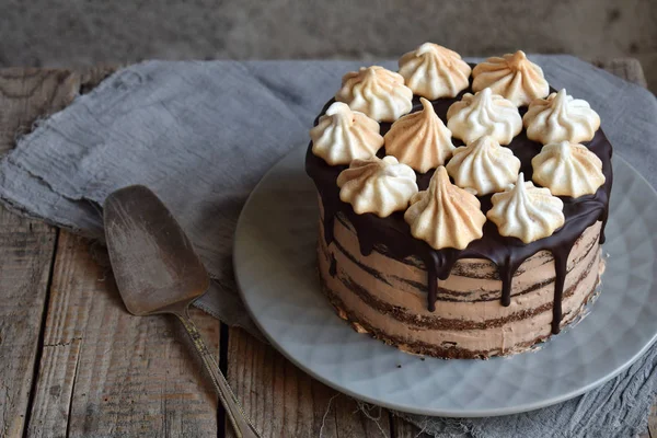 Chocolate cake decorated with rosettes of meringue cream: chocolate-nut biscuit, caramel cream. Homemade baking. — Stock Photo, Image