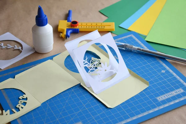 Haciendo un libro de túneles. Tarjeta de felicitación 3D Spring. Equipo de arte y herramientas para el corte de papel - cuchillo de corte, cortador de caja afilada, placa de corte azul, papel de origami. Estilo moderno del arte del papel del origami 3d . —  Fotos de Stock